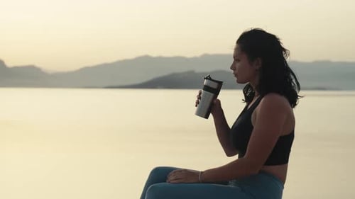 Athletic Caucasian Girl Drinking Coffee From a Hot Mug By the Ocean