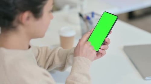Woman using Cell Phone With Green Screen At Desk