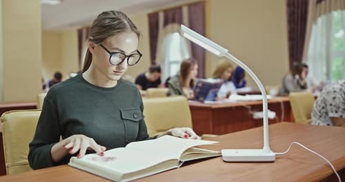 Pretty Female Student with Books Working in a High School Library