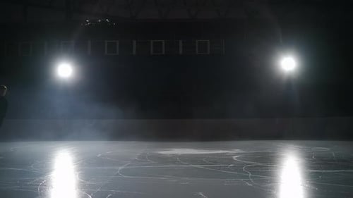Un patineur artistique seul patine sur une patinoire la nuit à l'entraînement sur un tir au Ralenti dans une arène vide