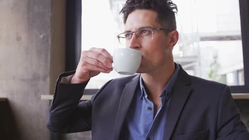 Caucasian businessman in thought, sitting at table drinking cup of coffee in cafe