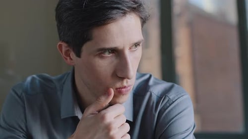 Front View Portrait Caucasian Millennial Business Man Sitting in Office Near Window Thinking About