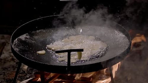 Potatoes Frying in Oil Over Campfire