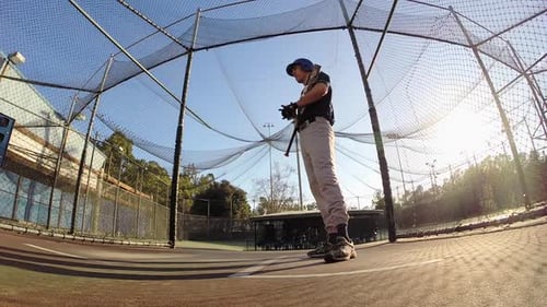 A baseball player practicing at the batting cages.
