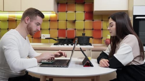 Couple Working on Computers in Bright Kitchen