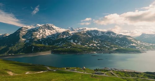 Time lapse: mountain peaks and emerald green alpine lake with moving clouds on the italian Alps