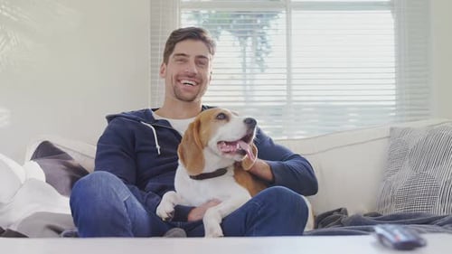 Man Holding a Beagle Dog on Couch