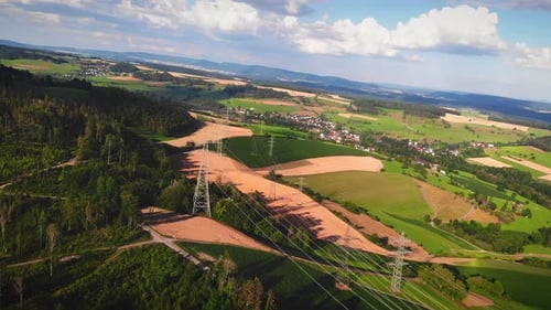 High voltage electricity towers and power lines at green and yellow wheat rural field