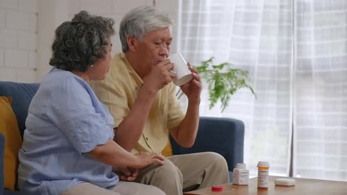 Senior Couple Taking Pills with Water Indoors