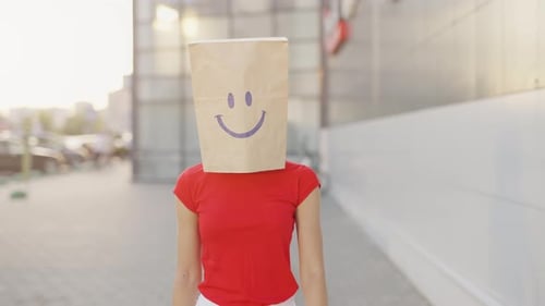 Woman With Paper Bag Walks on City Sidewalk
