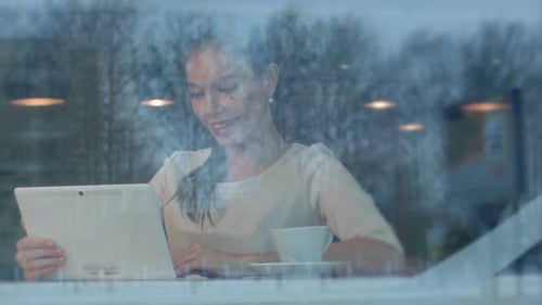 Beautiful Young Woman Using Tablet Pc To Make a Video Call in a Cafe