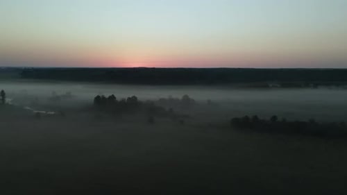 Foggy dawn in the countryside. Foggy river valley and rising sun. Aerial photography.