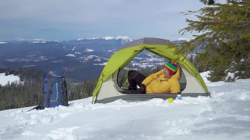 Tourist Relaxes in a Tent in the Mountains in Winter