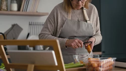 Woman peeling carrot at the kitchen table