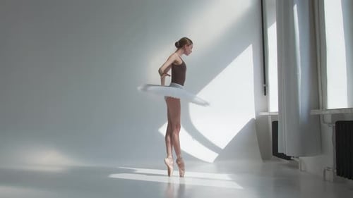 Young Ballerina Training in the Studio Standing By the Window, Flexible Girl on a White Background