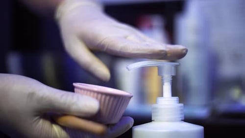 Dispensing Lotion Into Container With Gloved Hands