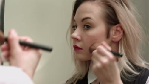 Blonde Woman Applying Makeup with Brush in Mirror