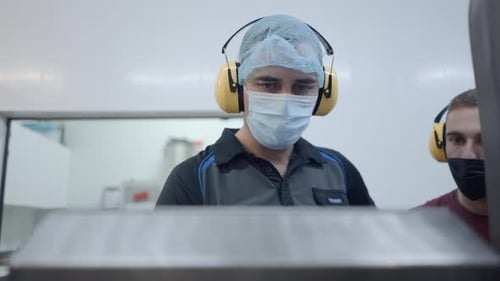 Beer Factory Operators Wearing Headphones And Facemasks At Their Workplace