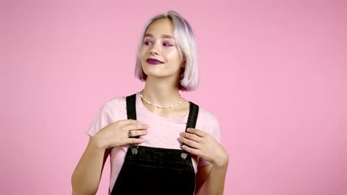 Attractive Hipster Woman with Colorful Purple Hair Smiling, Flirting To Camera Over Pink Wall