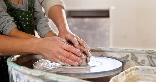 Child Learns Pottery from Adult on Wheel