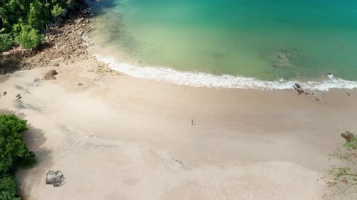 Drohnenschuss von Küste und Strandwasser, die gegen den Sand krachen