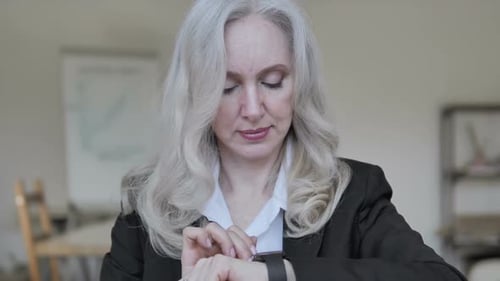 Senior Woman Uses Smart Watch in Office