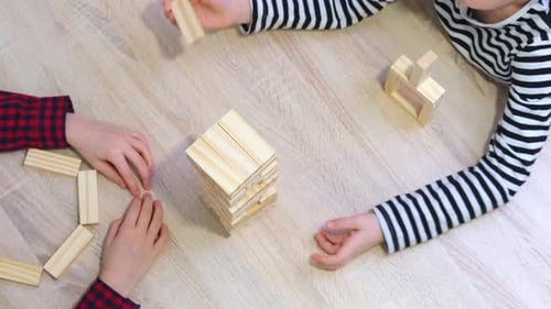Children Playing Wooden Block Removal Tower Game at Home
