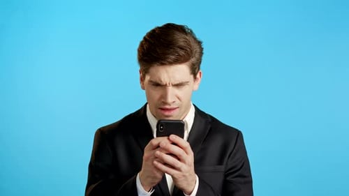 Man in Suit Uses Smartphone With Frustrated Expression