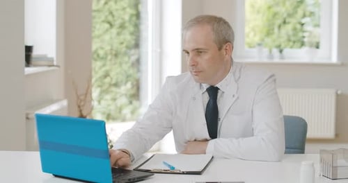 Medical Professional Working at Computer and Writing