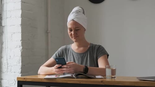 Close View Woman in Gray T-shirt Came Out of Shower with White Towel on Her Head. The Lady Sits and