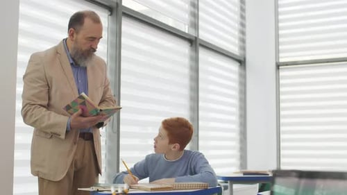 Teacher Reads to Student in Classroom