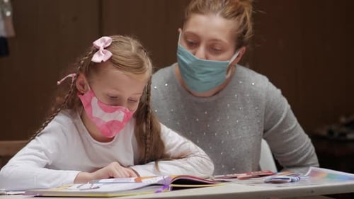 Child Reading with Mother Wearing Face Masks Indoors