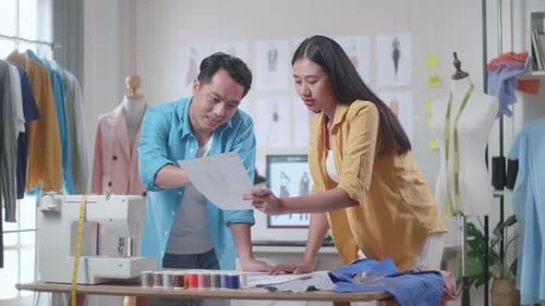Male And Female Designers Discussing About The Clothes Drawing Picture In Hand While Designing