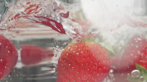 Frische Erdbeerfrüchte werden ins Wasser geworfen