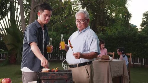 Happy Asian family having a barbecue-BBQ party together in the garden at home.