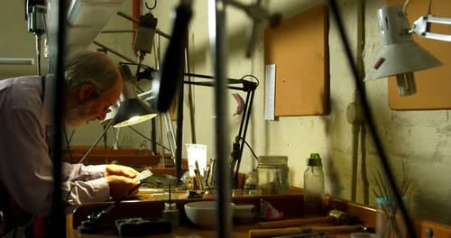 Goldschmied arbeitet am Schreibtisch in der Werkstatt