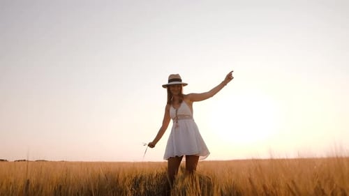 Happy Free Young Woman Dancing and Spinning Around in Slow Motion Across Field Touching Ears of