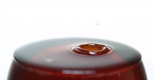 Goutte de vin rouge versée dans le verre, sur fond blanc, ralenti 4K
