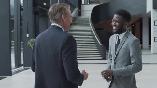 Two Diverse Friendly Businessmen Chatting in Office Hallway