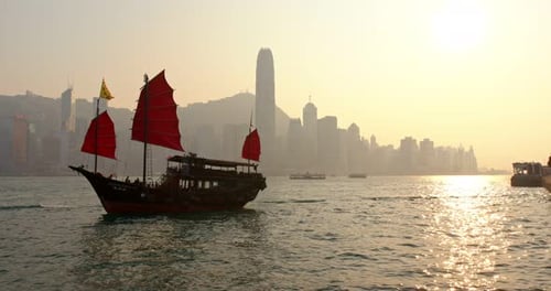 Sunset skyline of Hong Kong with traditional cruise sailboat at Victoria harbor