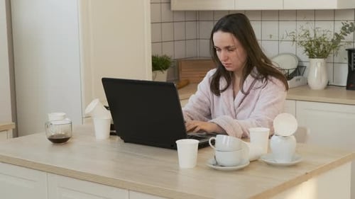 Woman Working on Laptop in Kitchen at Home