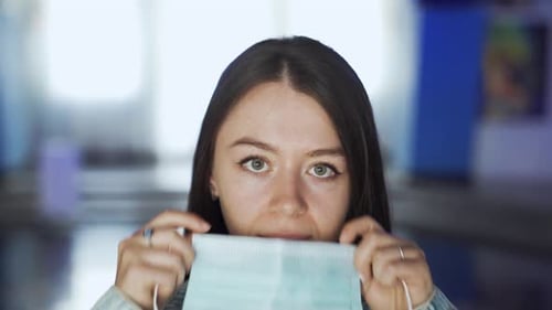 Woman puts on mask at the entrance of a movie theater