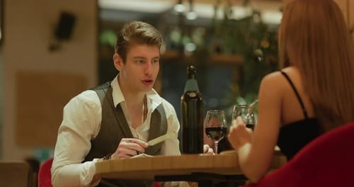 Young Man Talking to a Girl at a Restaurant Table