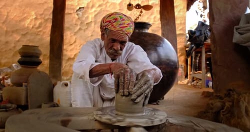 Potier indien au travail : lancer le volant du potier et façonner un récipient en céramique et des articles en argile : pot