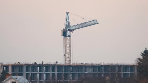 Silueta oscura de Tower Crane y pequeñas siluetas de trabajadores en un apartamento residencial alto
