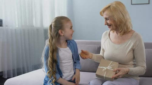 Loving Girl Giving Birthday Gift to Woman