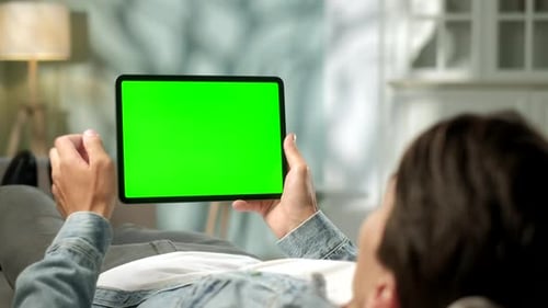 View From the Shoulder of Man Holding and Using Hand Gestures on Green Mock-up Screen Digital Tablet