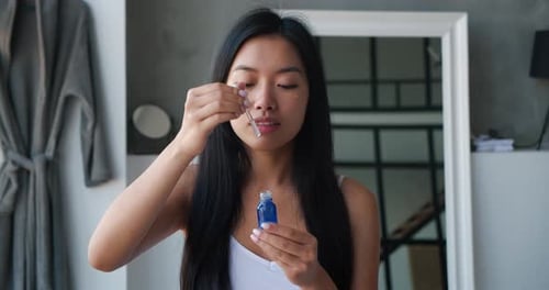 Young Woman Applies Serum to Face Indoors