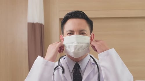 Asian male doctor removing surgical mask on to prevent covid-19 virus pandemic in hospital.