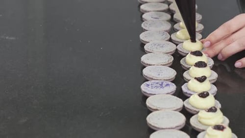 Assembling Macarons With Cream and Blackberry Jam